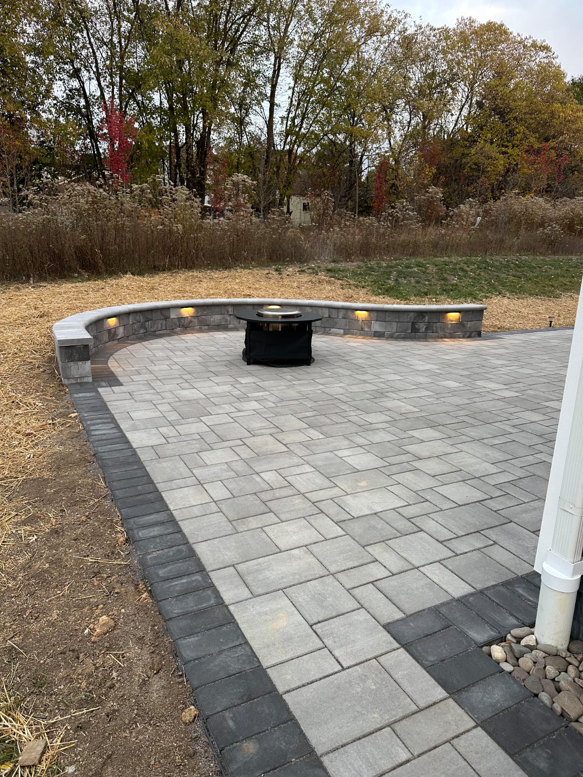 Curved paver patio with a built-in seating wall and fire pit