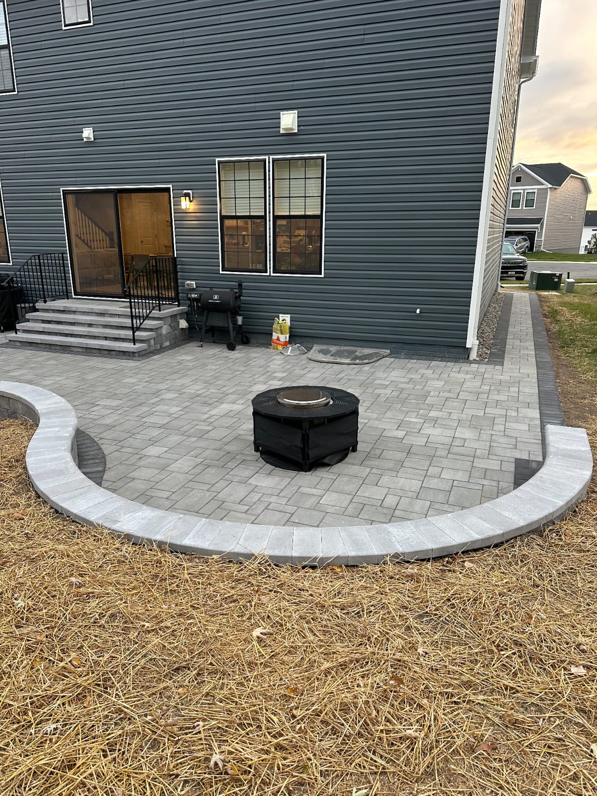 Paver patio with a curved border, built around a fire pit