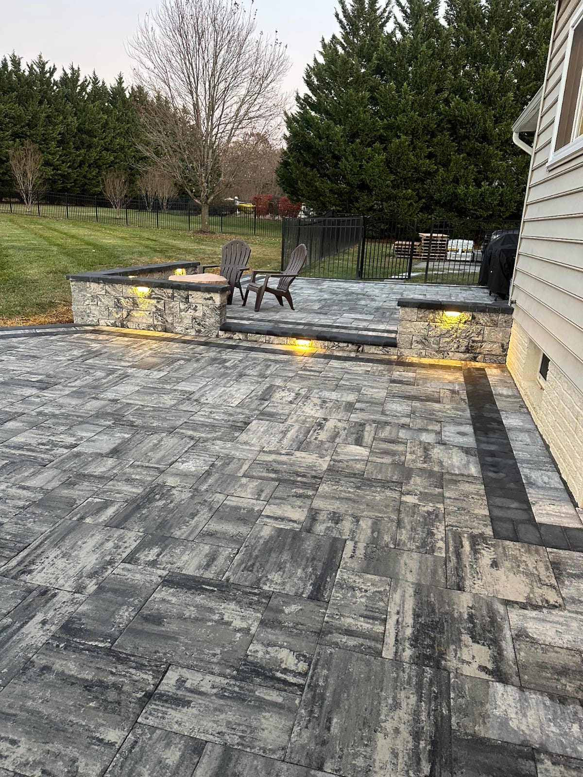 Multi-level paver patio with stone retaining walls and integrated lighting